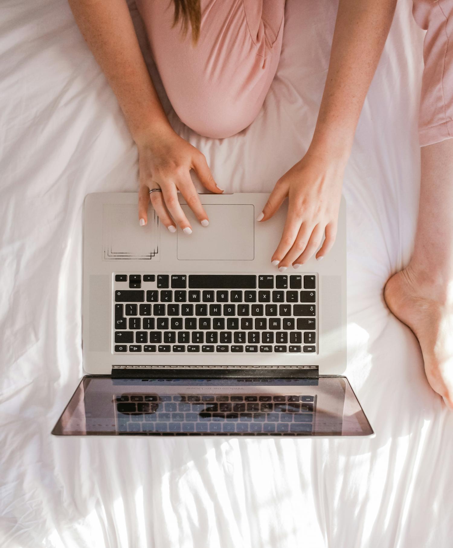woman and laptop on bed